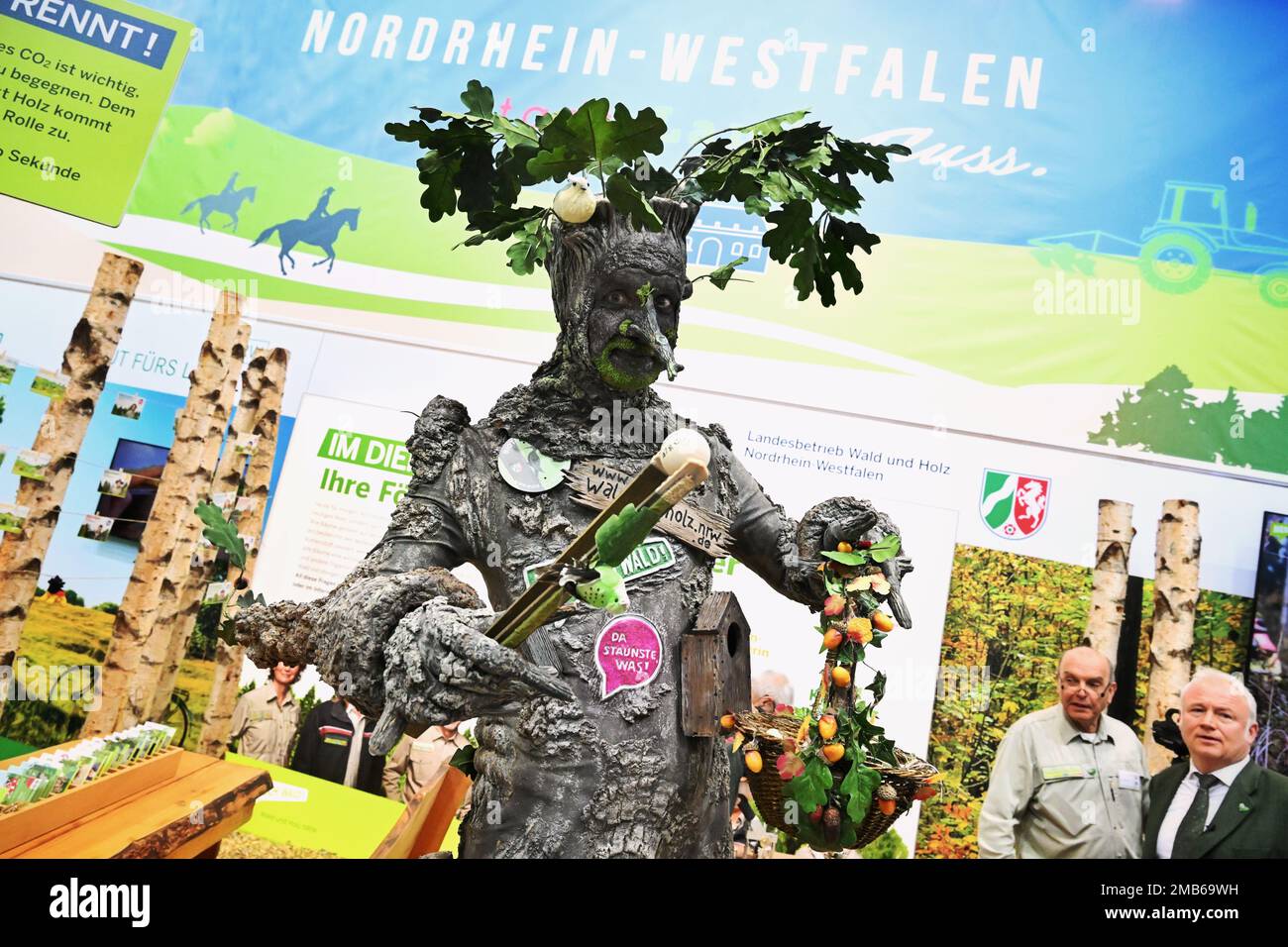 Berlino, Germania. 20th Jan, 2023. Un uomo vestito come un albero gnarled si trova presso lo stand dell'Ufficio statale per le foreste e il legno nella sala espositiva della Renania settentrionale-Vestfalia dopo l'apertura della settimana verde internazionale (IGW). La più grande fiera del mondo per l'alimentazione, l'agricoltura e l'orticoltura esiste dal 1926, e dal 1996 si tiene anche la fiera commerciale e informativa "Heim-Tier & Pflanze". L'edizione di quest'anno termina il 29. 01,2023. Credit: Soeren Stache/dpa/Alamy Live News Foto Stock