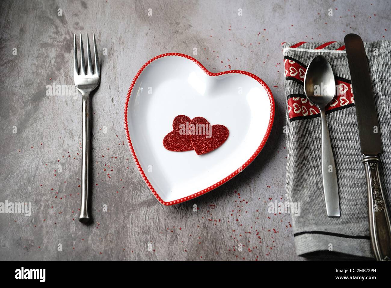Tavolo di San Valentino con piatto a forma di cuore cucchiaio coltello forchetta e tovagliolo Foto Stock