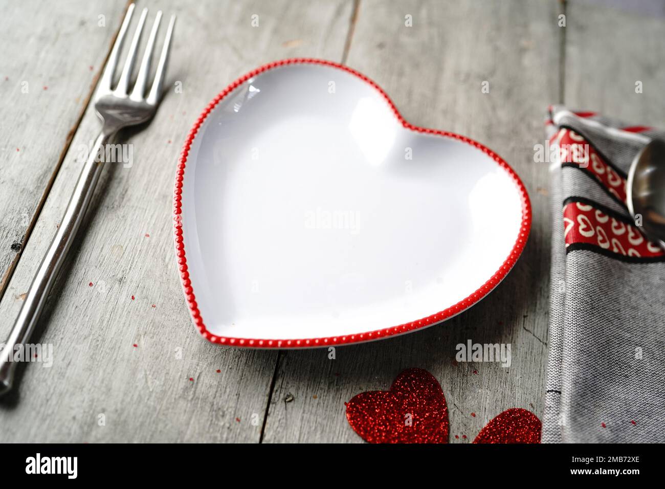 Tavolo di San Valentino con piatto a forma di cuore cucchiaio coltello forchetta e tovagliolo Foto Stock