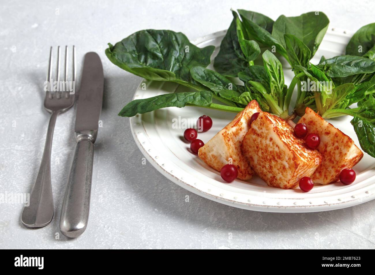 Mozzarella alloumi alla griglia con spinaci verdi e mirtilli rossi con posate Foto Stock
