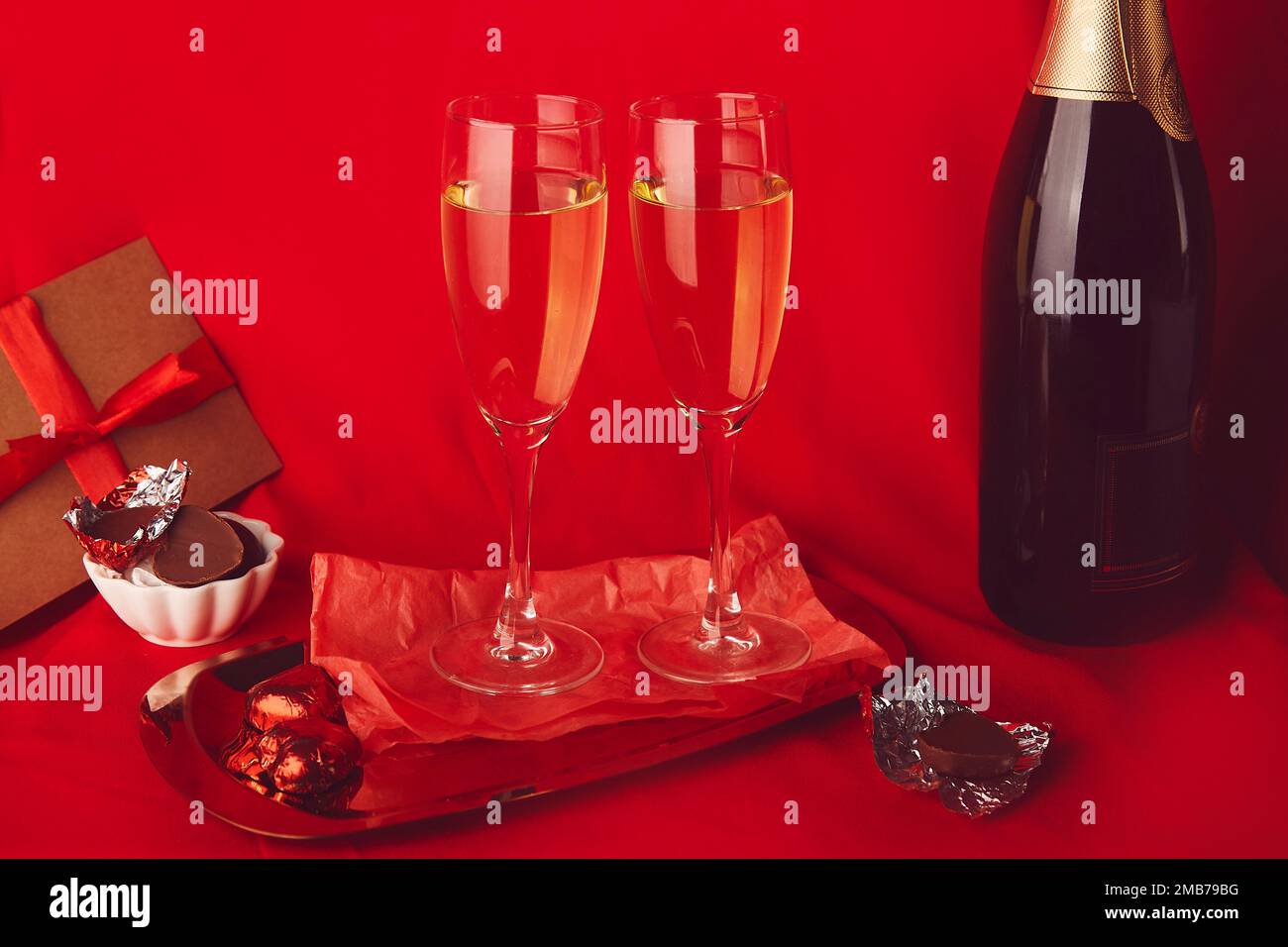 Tradizionale sfondo giorno di San Valentino. Cena romantica di stagione rossa con omaggio, cartolina, champagne e caramelle al cioccolato. Foto Stock