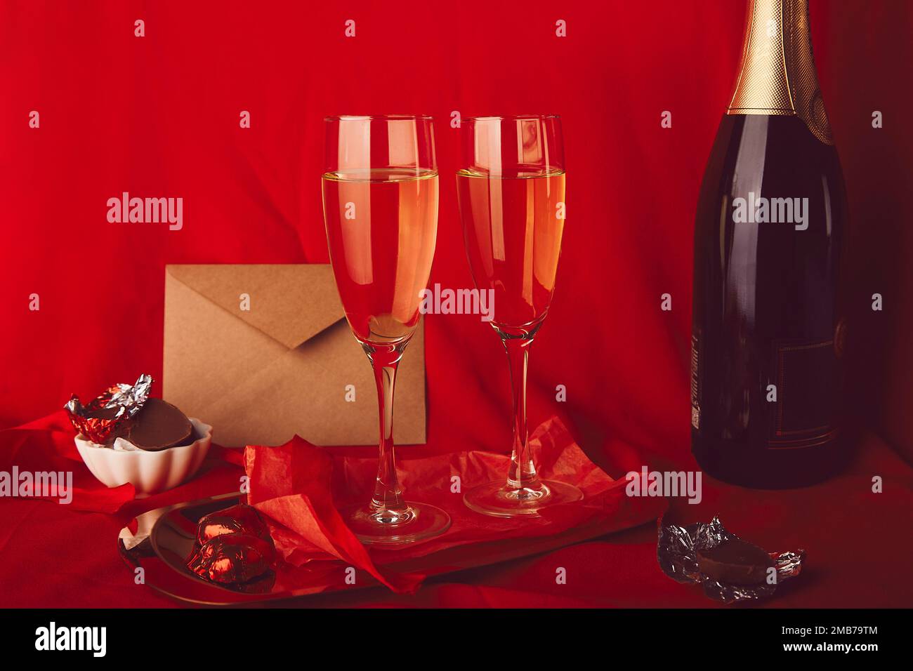 Tradizionale San Valentino sfondo estetico. Cena romantica rossa stagionale con omaggio, cartolina, champagne e caramelle a forma di cuore al cioccolato. Foto Stock