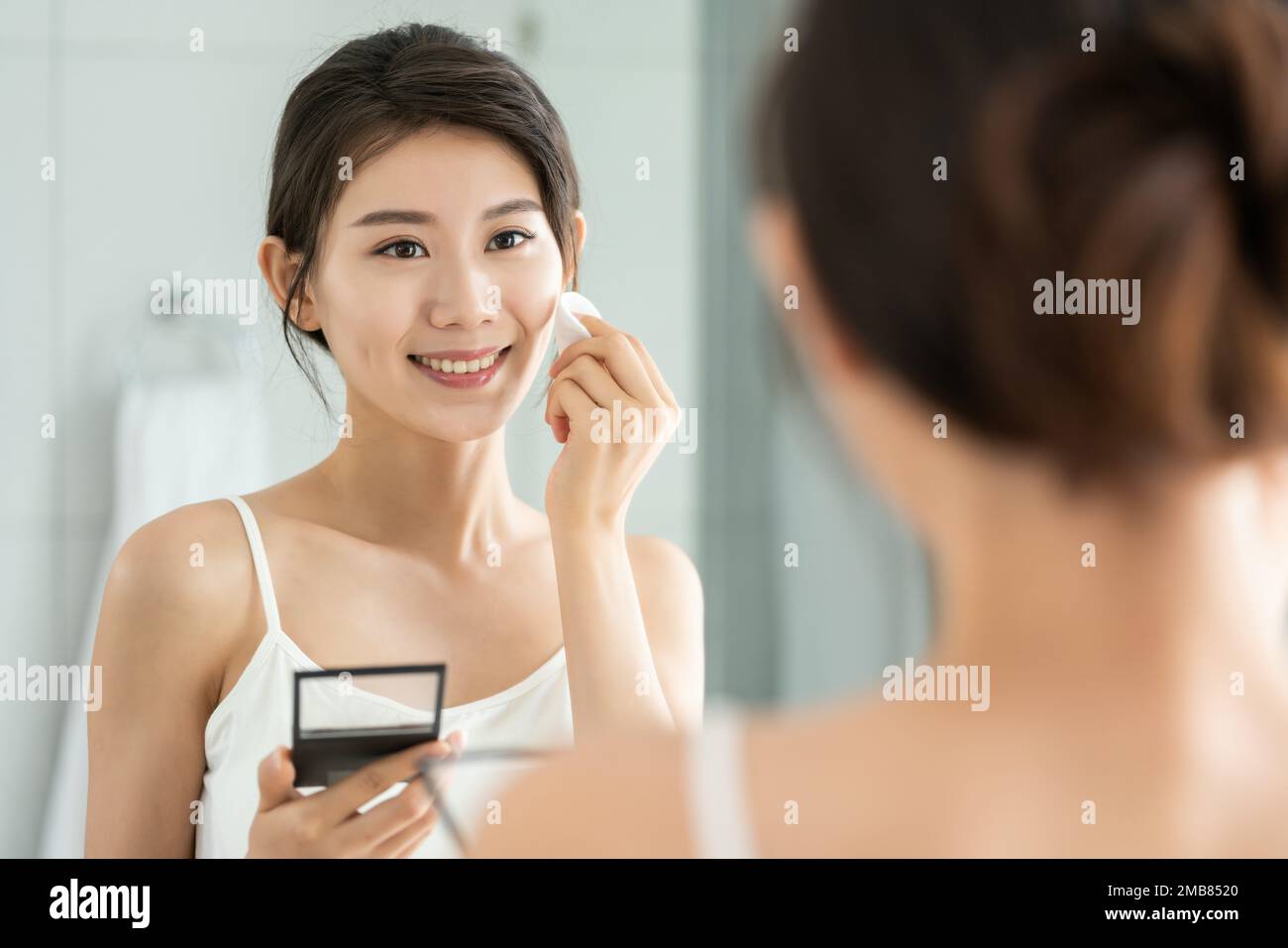 La giovane donna trucco in bagno Foto Stock