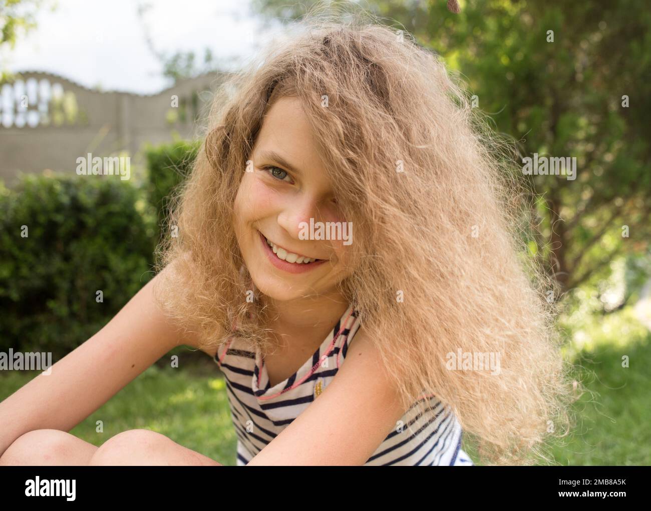 Ritratto di una bella ragazza sorridente di 12 anni nel parco all'aperto. Godetevi il momento, l'intenzione positiva, il gioioso umore estivo Foto Stock