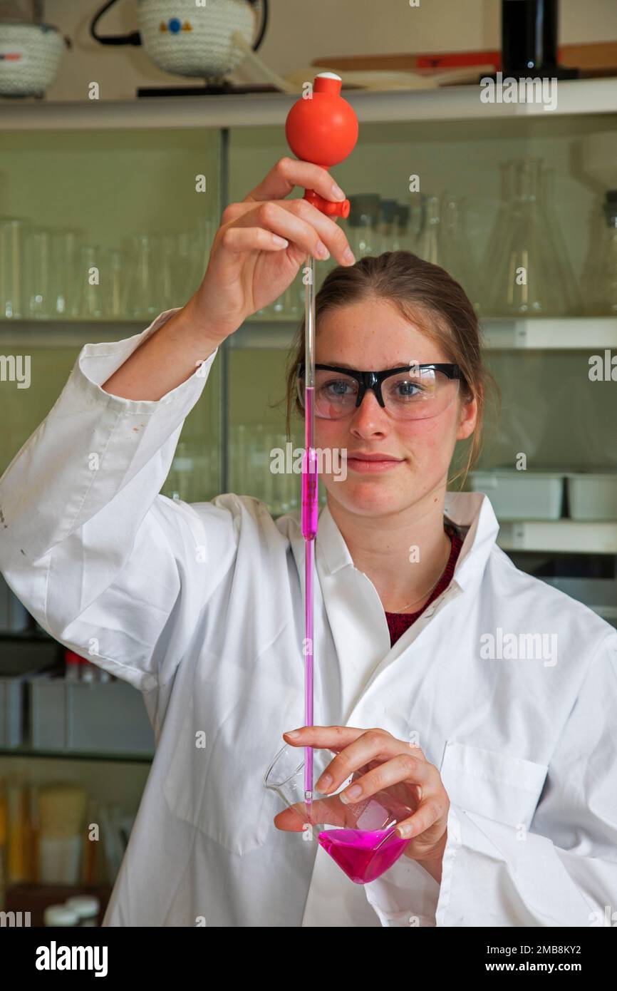 Paesi Bassi, gli studenti delle scuole superiori utilizzano una palla di gomma per aspirare il liquido dal becher in una pipetta. Foto Stock