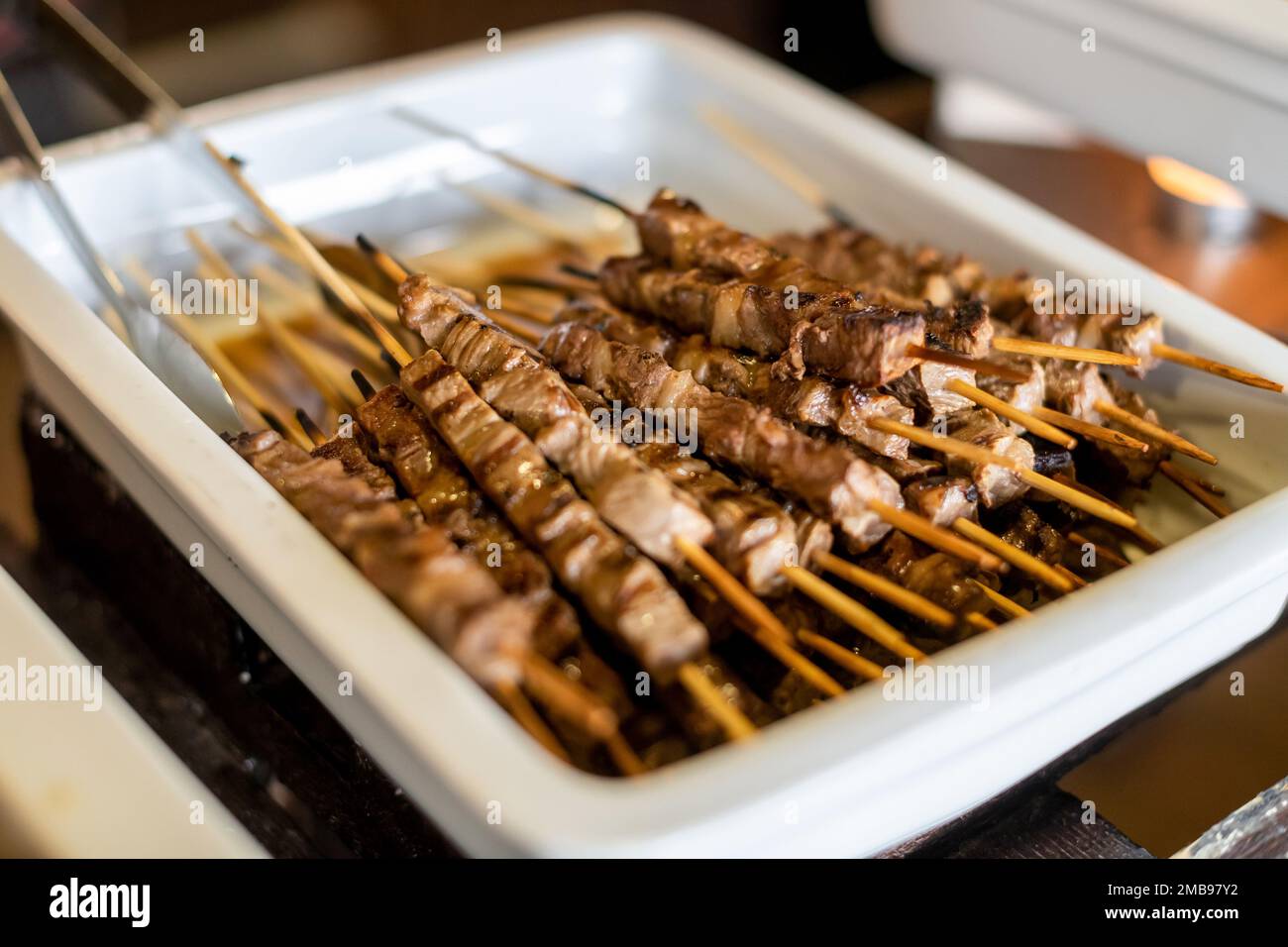 Angolo alto di appetitosi pezzi di agnello alla griglia su spiedini posti su contenitore bianco Foto Stock
