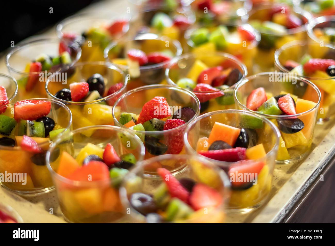 Angolo alto di Macedonia di frutta in ciotole di vetro composto da fragole a fette kiwi mango e uva Foto Stock