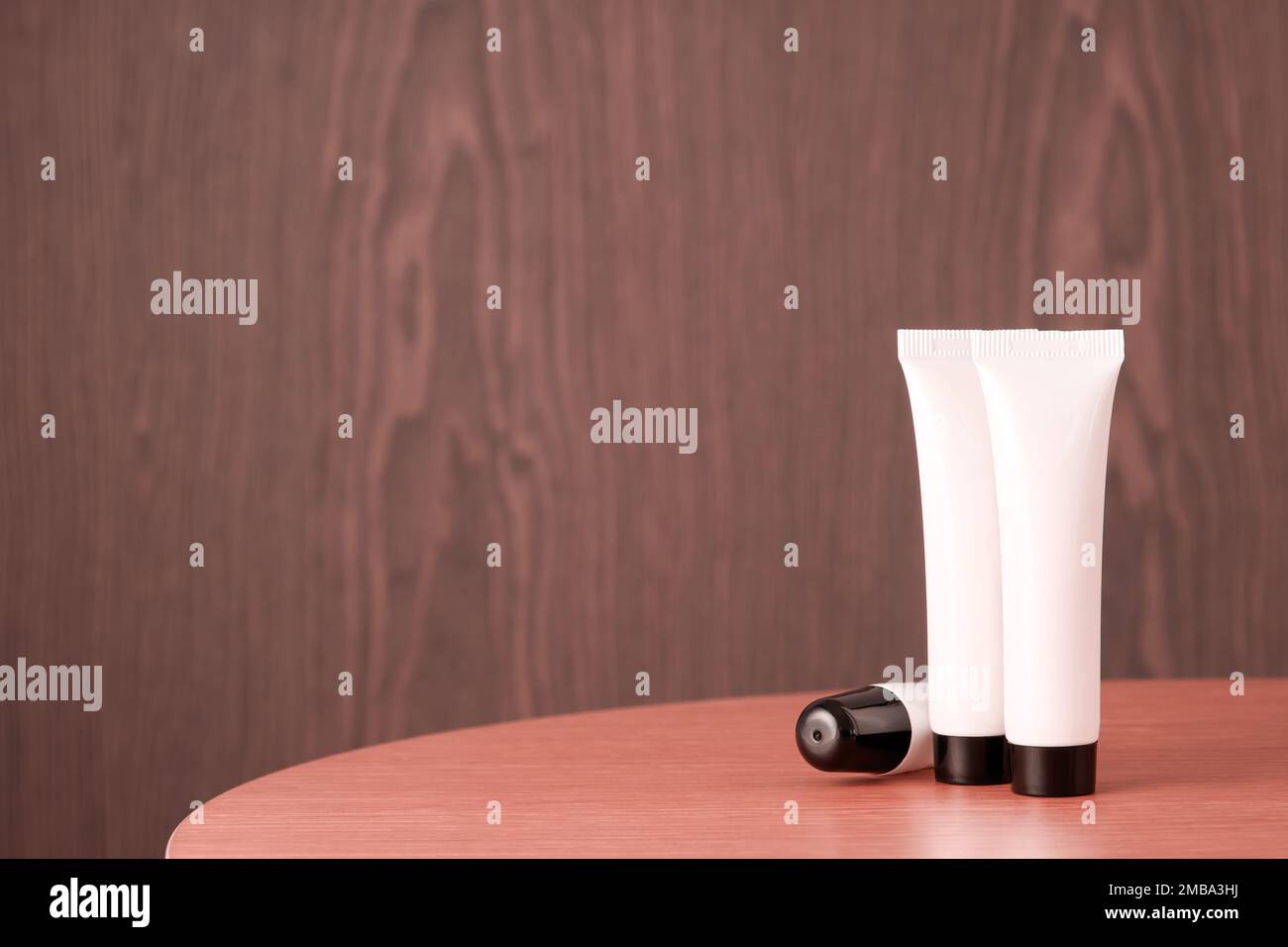 Bottiglie bianche in plastica cosmetica con uno spazio libero per il testo dell'etichetta sul tavolo di legno. Centro benessere e tema moda. Copia spazio per la pubblicità Foto Stock