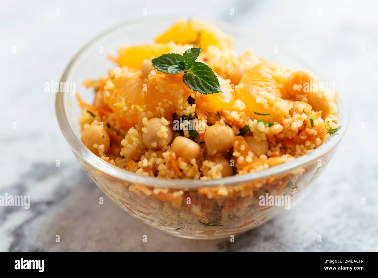 Insalata sana con couscous, tangerini, pezzi d'arancia, ceci, prezzemolo e menta fresca. Foto Stock