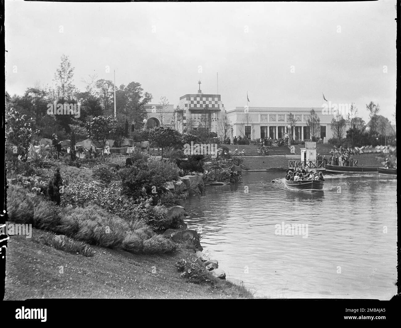 Wembley Park, Brent, Greater London Authority, 1924. Vista sul lago, sul palco e sul padiglione del Sudafrica al British Empire Exhibition di Wembley Park, con una barca piena di persone sul lago che passa davanti a un giardino roccioso. La British Empire Exhibition è stata inaugurata il giorno 1924 di San Giorgio con l'obiettivo di stimolare il commercio e rafforzare i legami tra i paesi dell'Impero britannico. Foto Stock