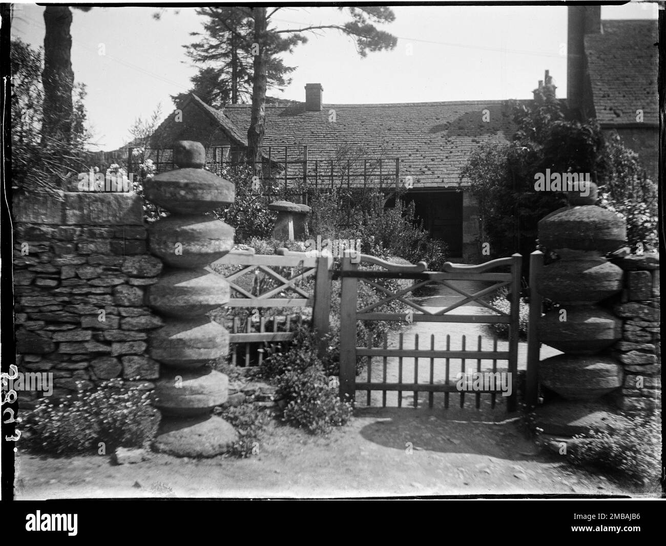 Monks Barn, Maugersbury, Cotswold, Gloucestershire, 1928. Il cancello moli e porta a Monks Barn visto davanti. I pontili di gate in questa fotografia possono essere stati costruiti attaccando insieme i tappi da pietre a sella. Nel giardino si possono vedere anche due pietre complete. Foto Stock