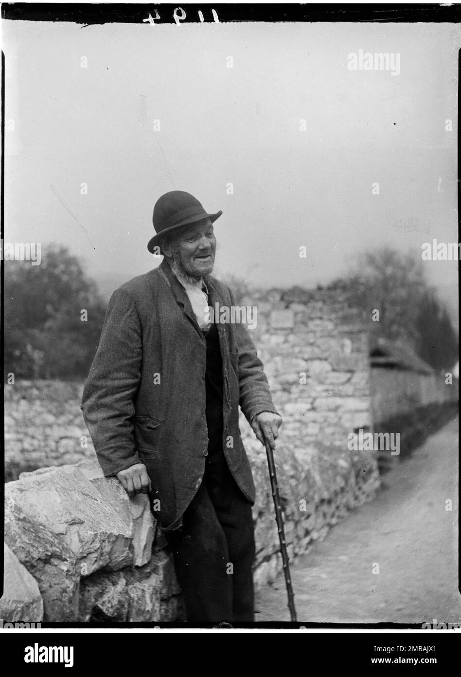 Cheddar, Sedgemoor, Somerset, 1907. Un uomo anziano che riposa contro un muro di pietra su un ponte di Cheddar. Foto Stock