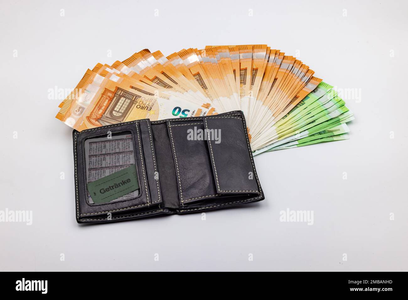 Ricchezza in una borsa con un fan di banconote in euro su uno sfondo bianco in studio Foto Stock