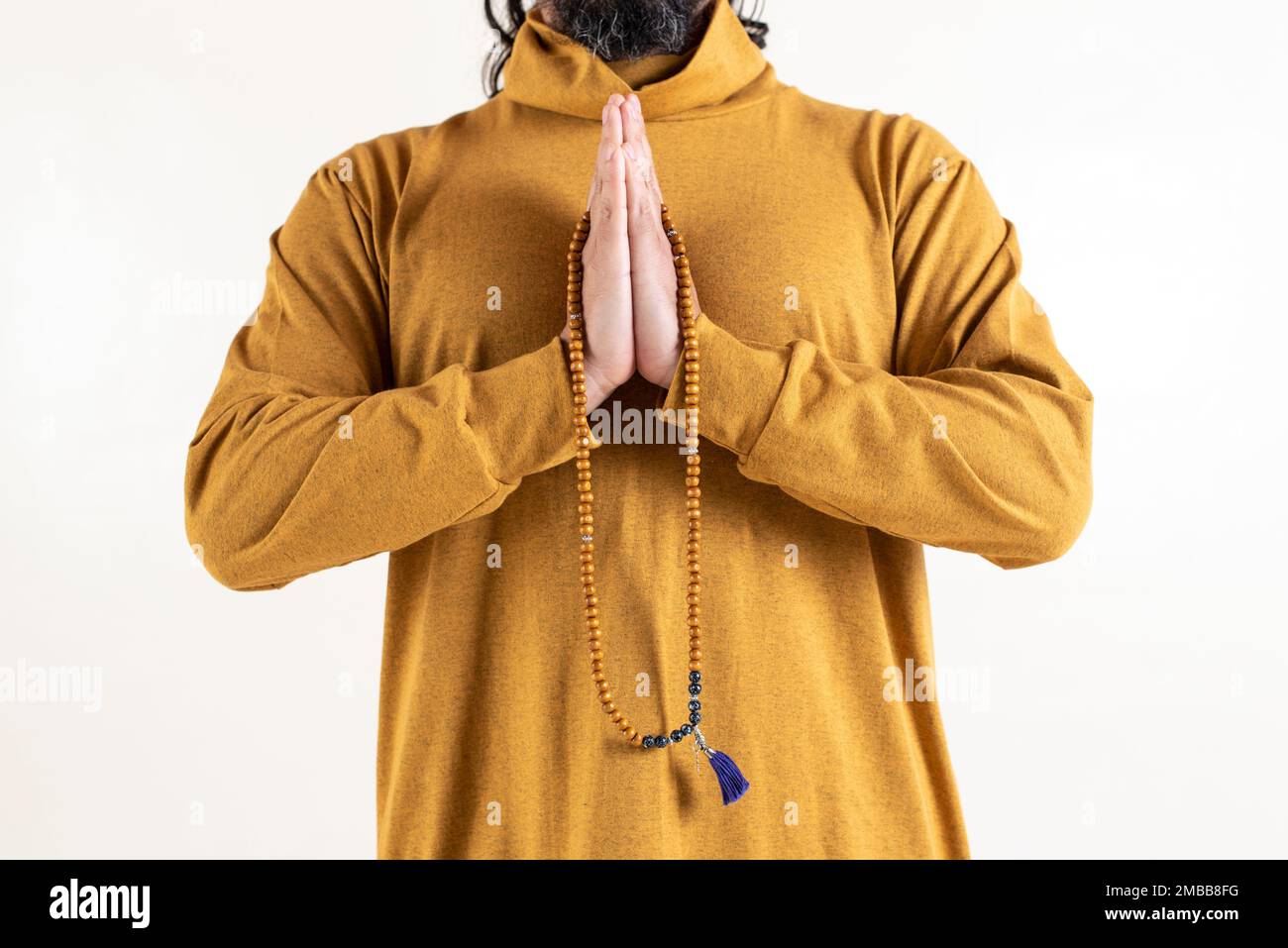 Primo piano di un uomo che stringe le mani mentre tiene una japa mala su sfondo bianco. Foto Stock