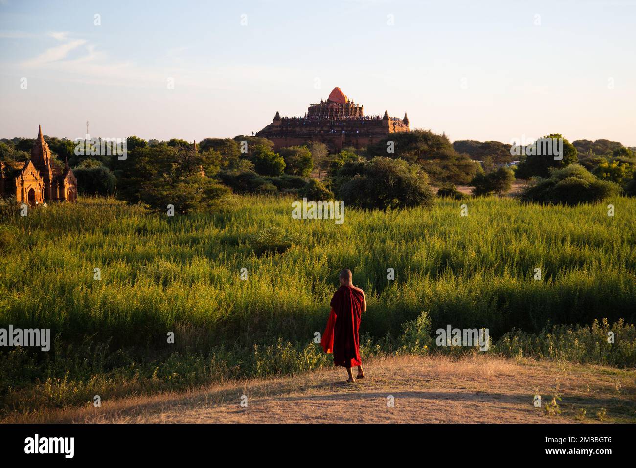 Monaco in abito rosso gode delle vedute durante un bel tramonto serale, Old Bagan ( Bagan ပုဂံ ) Myanmar Foto Stock