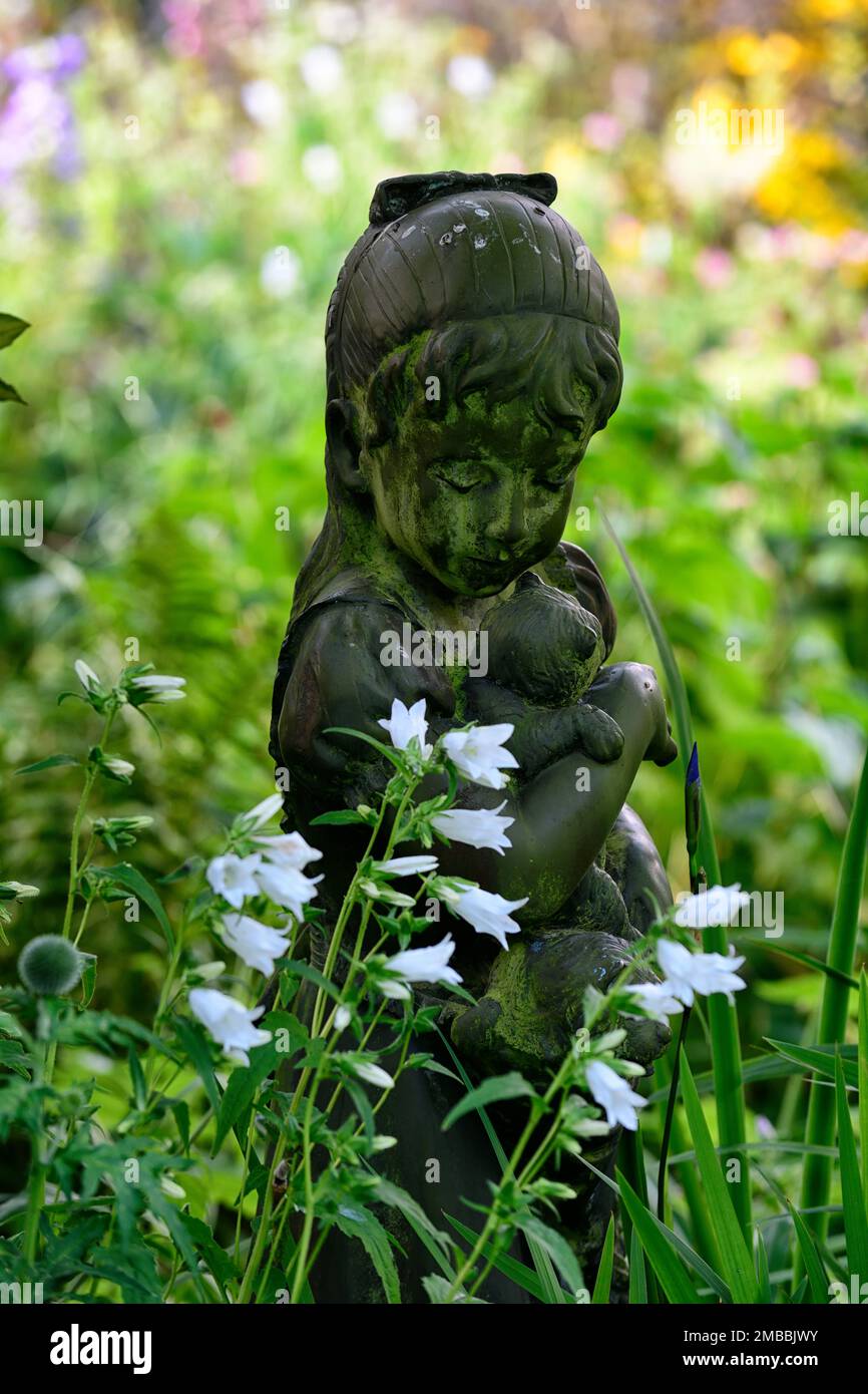Statua di un bambino in un giardino, giardino, giardino boschivo, ombra, ombreggiato, caratteristica giardino, statua ragazza, figurina bambino, RM Floral Foto Stock
