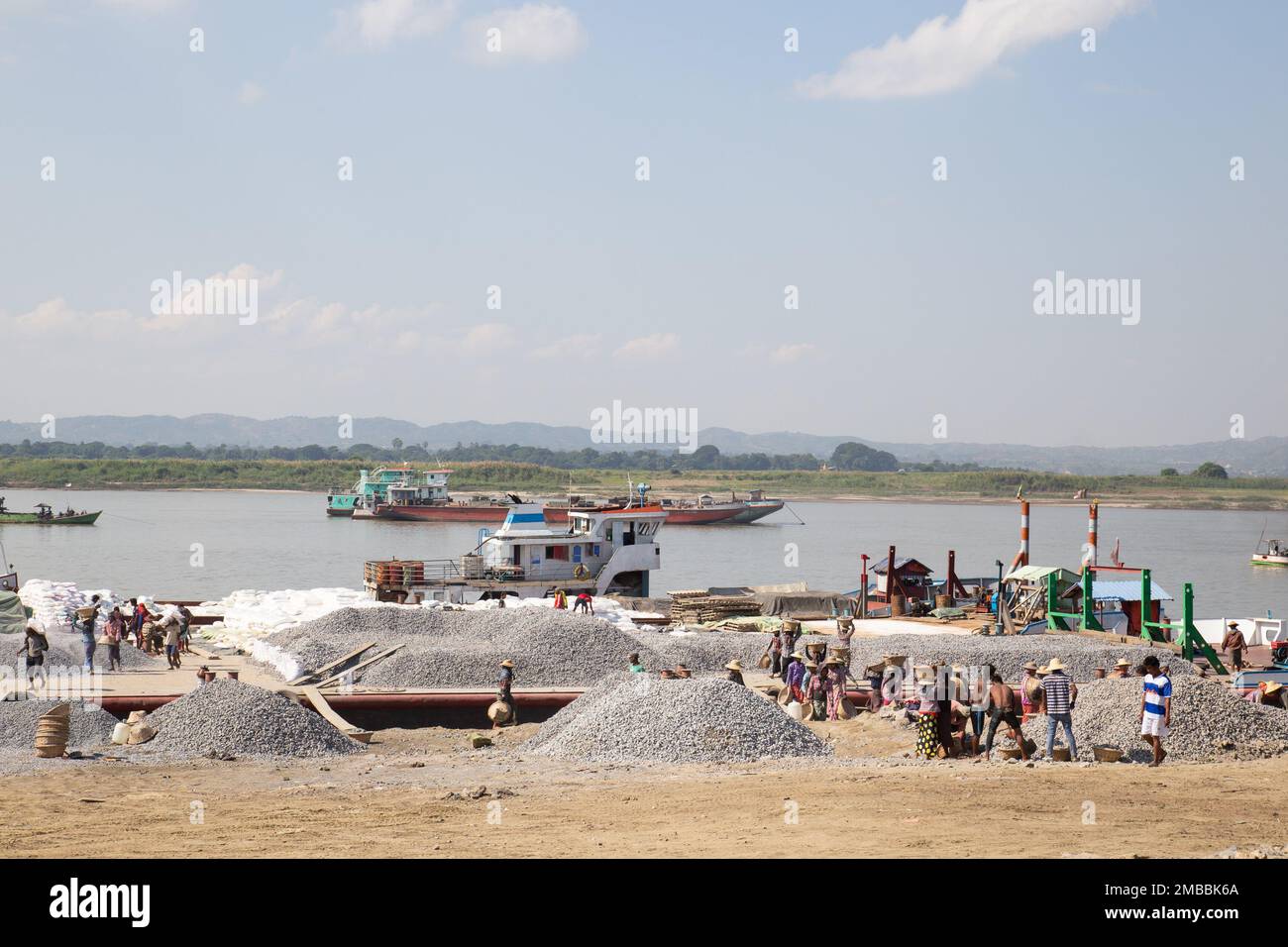 Workers Transport Gravel - lavori pesanti che scaricano la ghiaia dalle barche sul fiume Irrawaddy ( fotogiornalismo ) Mandalay , Myanmar Foto Stock