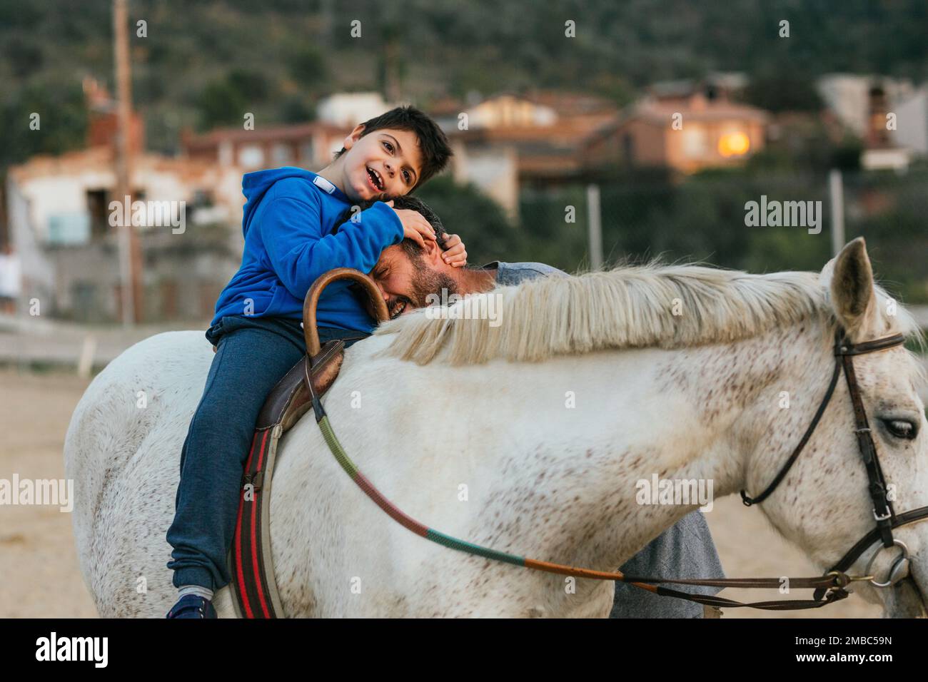 ragazzo con disabilità che abbraccia il suo fisioterapista durante la sessione di terapia equina Foto Stock