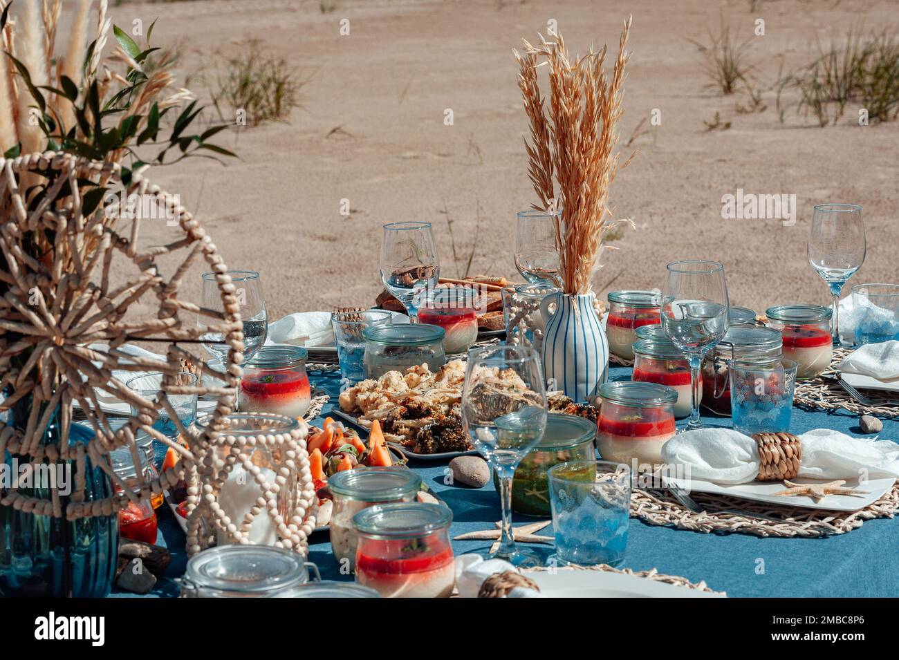 Cibo gustoso per picnic estivo all'aperto. Deliziosi antipasti e dessert in vasetti. Pranzo sulla spiaggia sul mare. Foto Stock