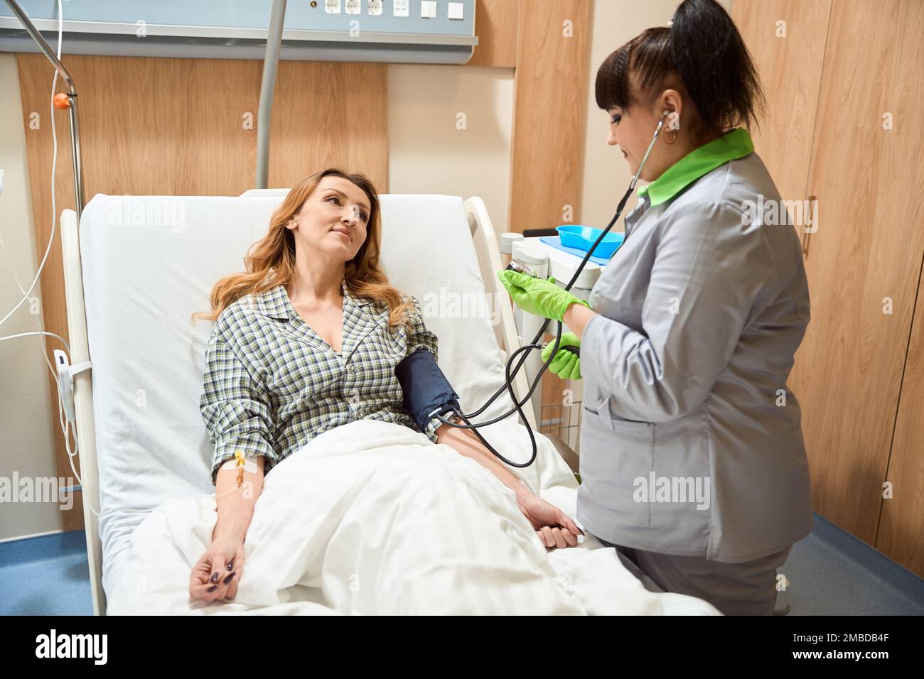 Donna che riposa in ospedale durante il trattamento, guardando il medico Foto Stock