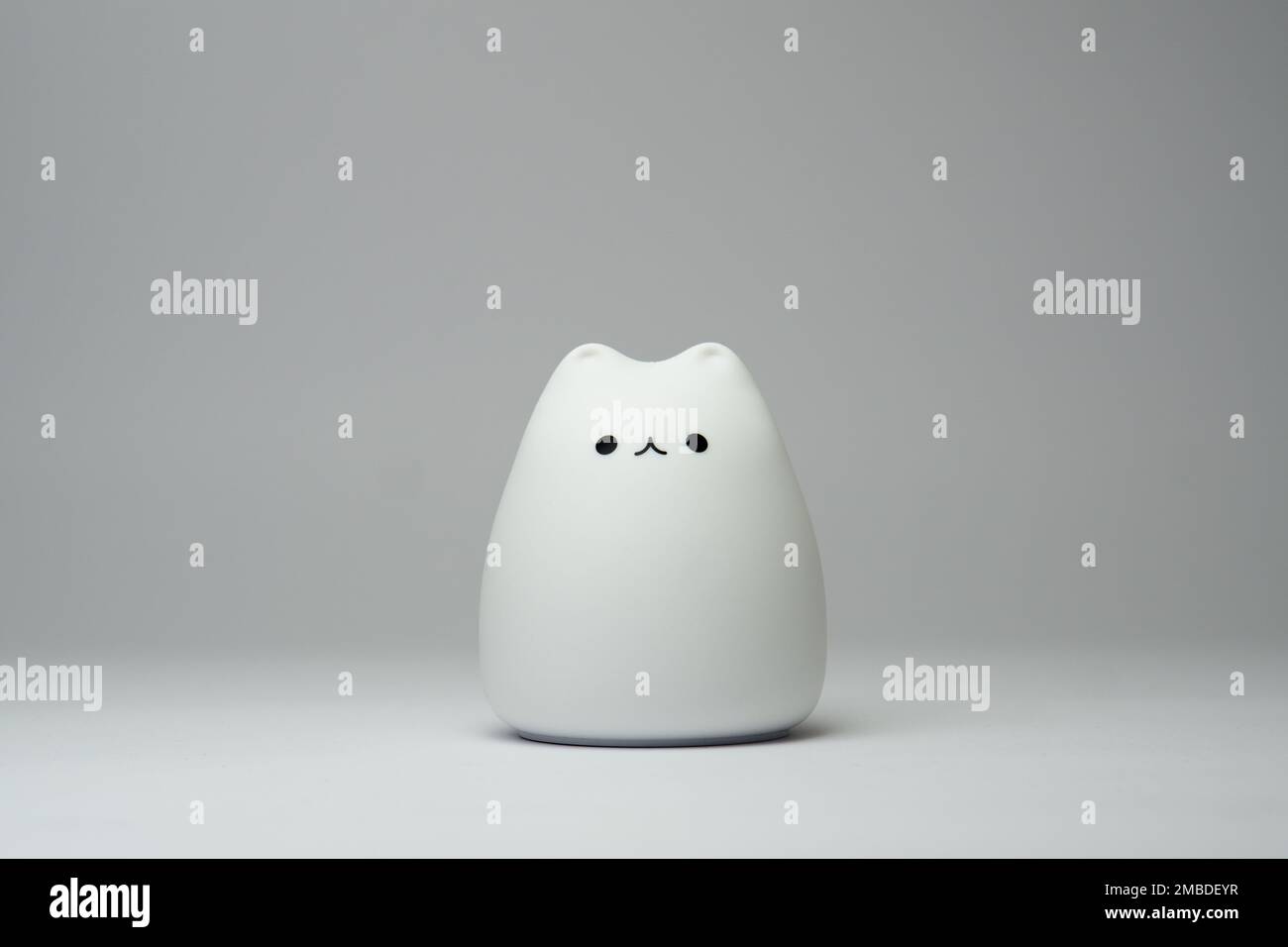 Lampada bianca a forma di gatto su sfondo bianco. Graziosa lampada in silicone a forma di gatto su sfondo bianco. Foto Stock