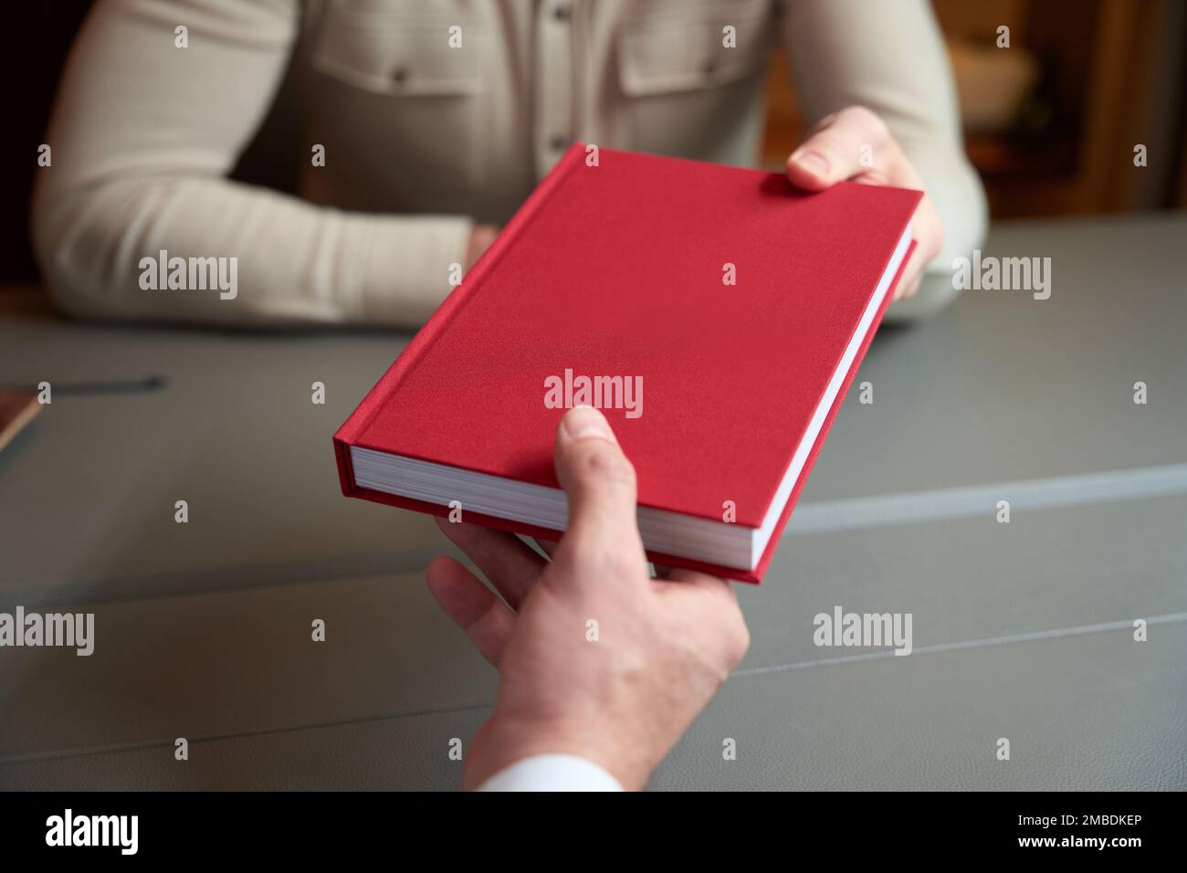L'uomo dà un libro rosso a un collega Foto Stock