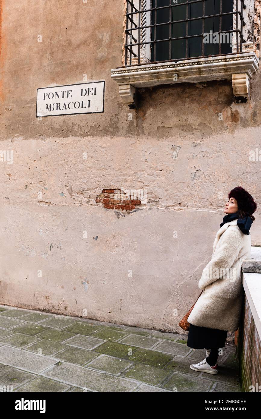 21 gennaio 2023. Ponte dei Miracoli, Venezia. Una bella donna con gli occhi chiusa in un cappello russo su un ponte di miracoli in un inverno deserto Venezia. Foto Stock