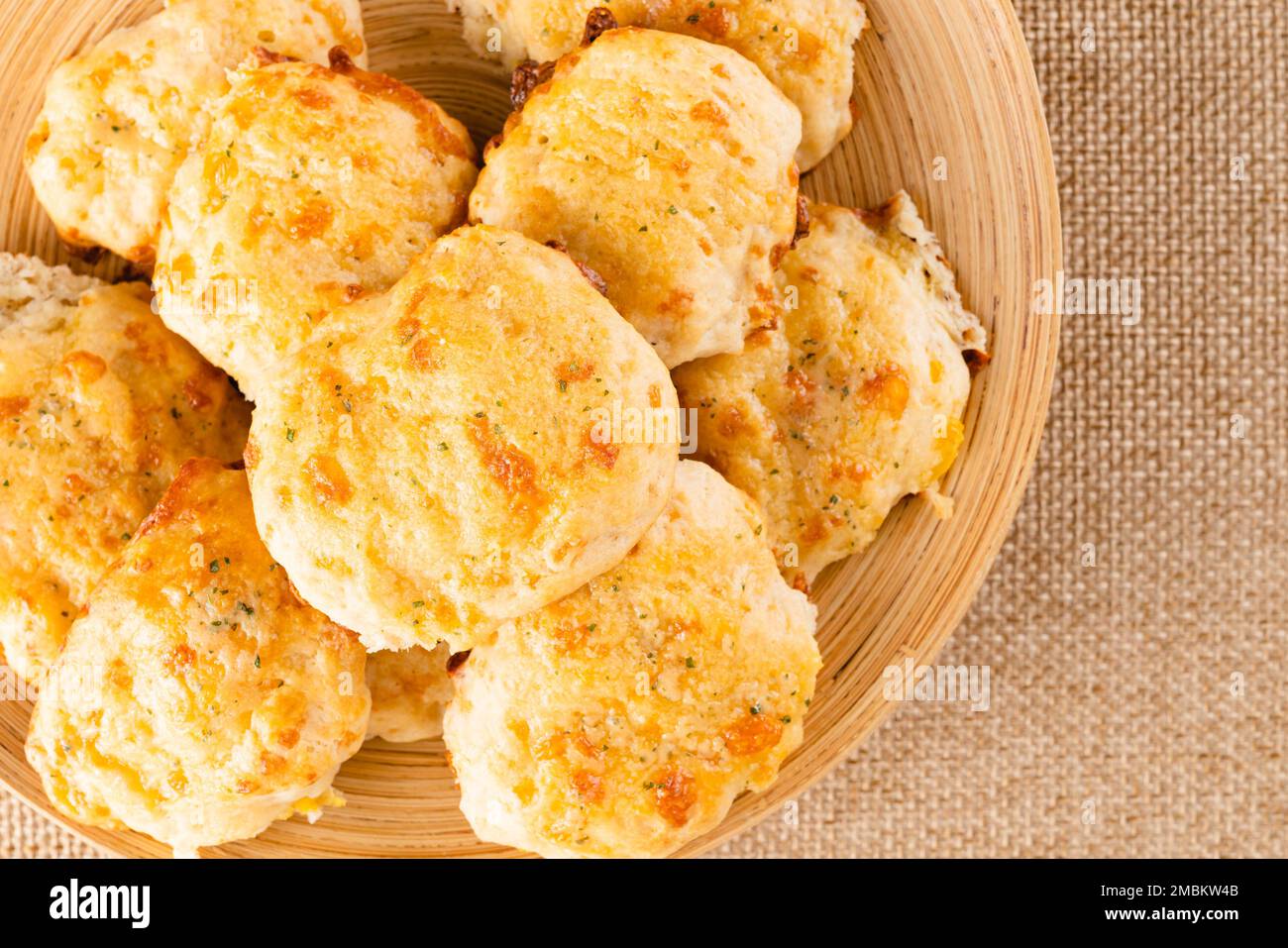 Biscotti al formaggio appena sfornati primo piano su un piatto di legno, piatto con spazio per le copie Foto Stock