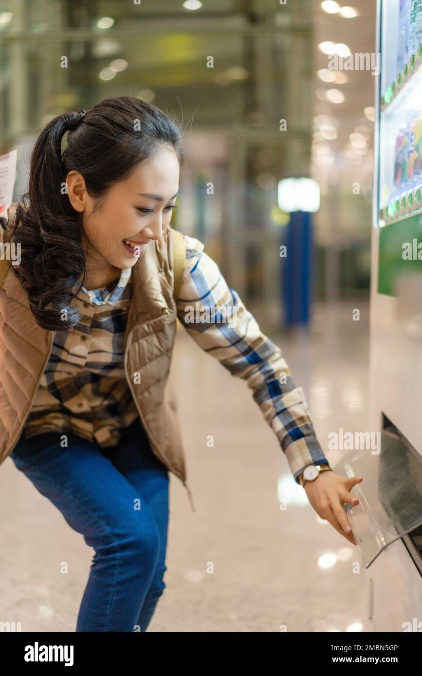 Le giovani donne usano una macchina self-service per acquistare bevande Foto Stock