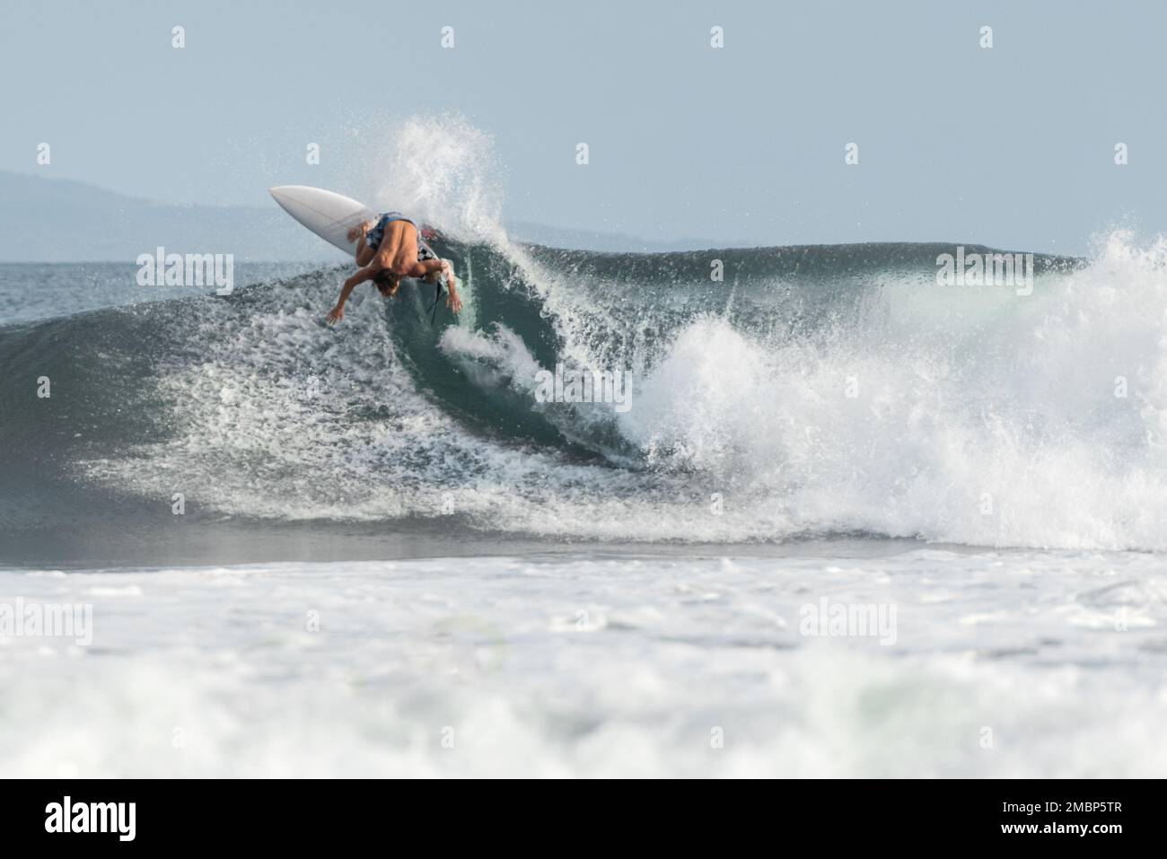 Surf a Keramas Beach, Bali, Indonesia, uomo e donna surf onde con un surf board, imparare surf a Kuta e Uluwatu Foto Stock