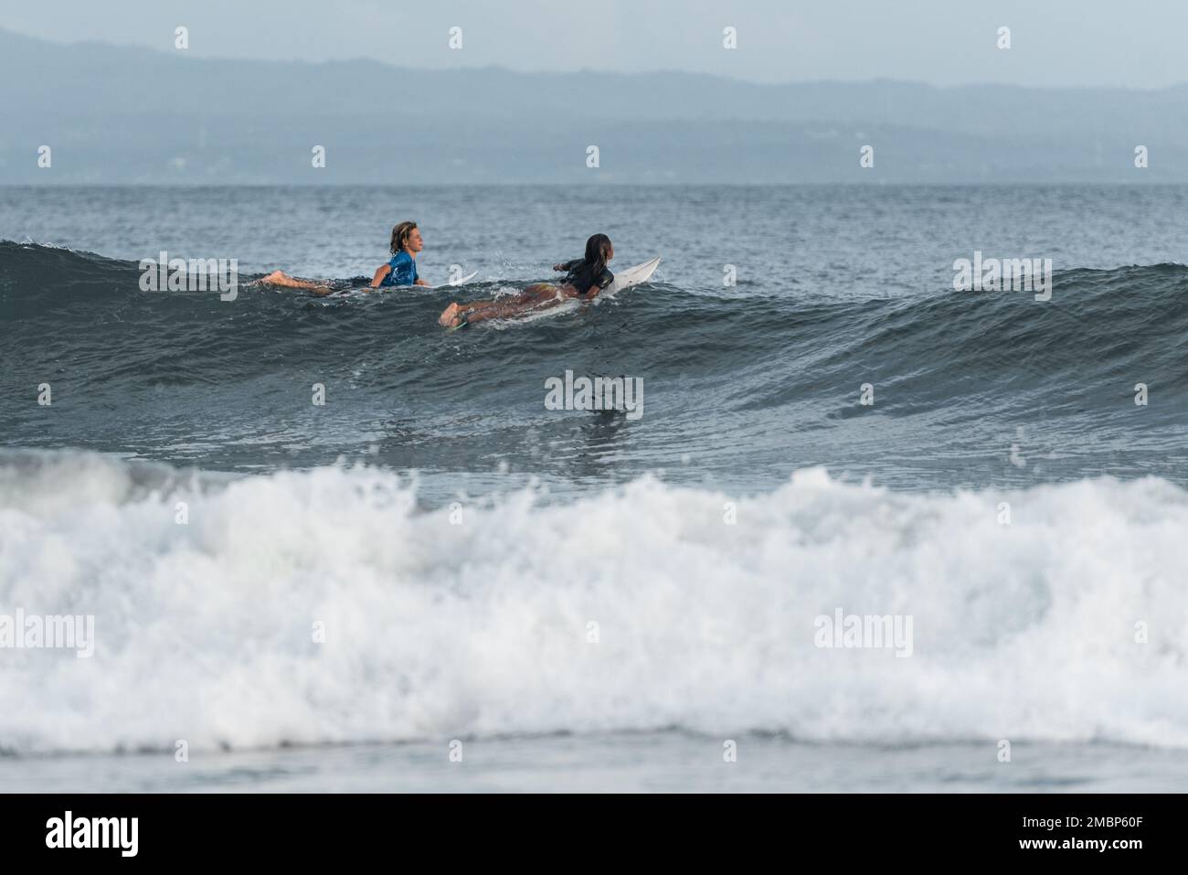 Surf a Keramas Beach, Bali, Indonesia, uomo e donna surf onde con un surf board, imparare surf a Kuta e Uluwatu Foto Stock