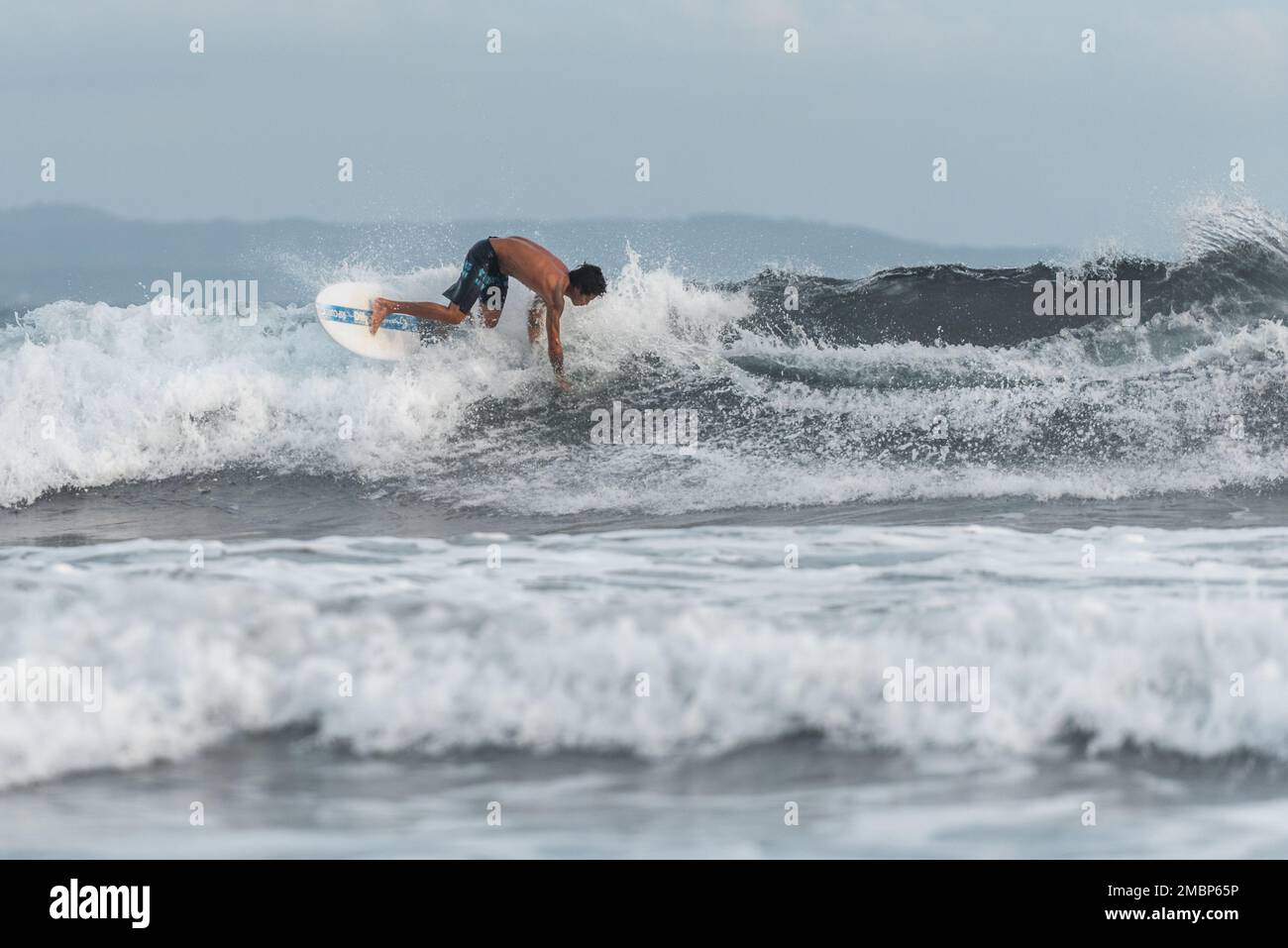 Surf a Keramas Beach, Bali, Indonesia, uomo e donna surf onde con un surf board, imparare surf a Kuta e Uluwatu Foto Stock