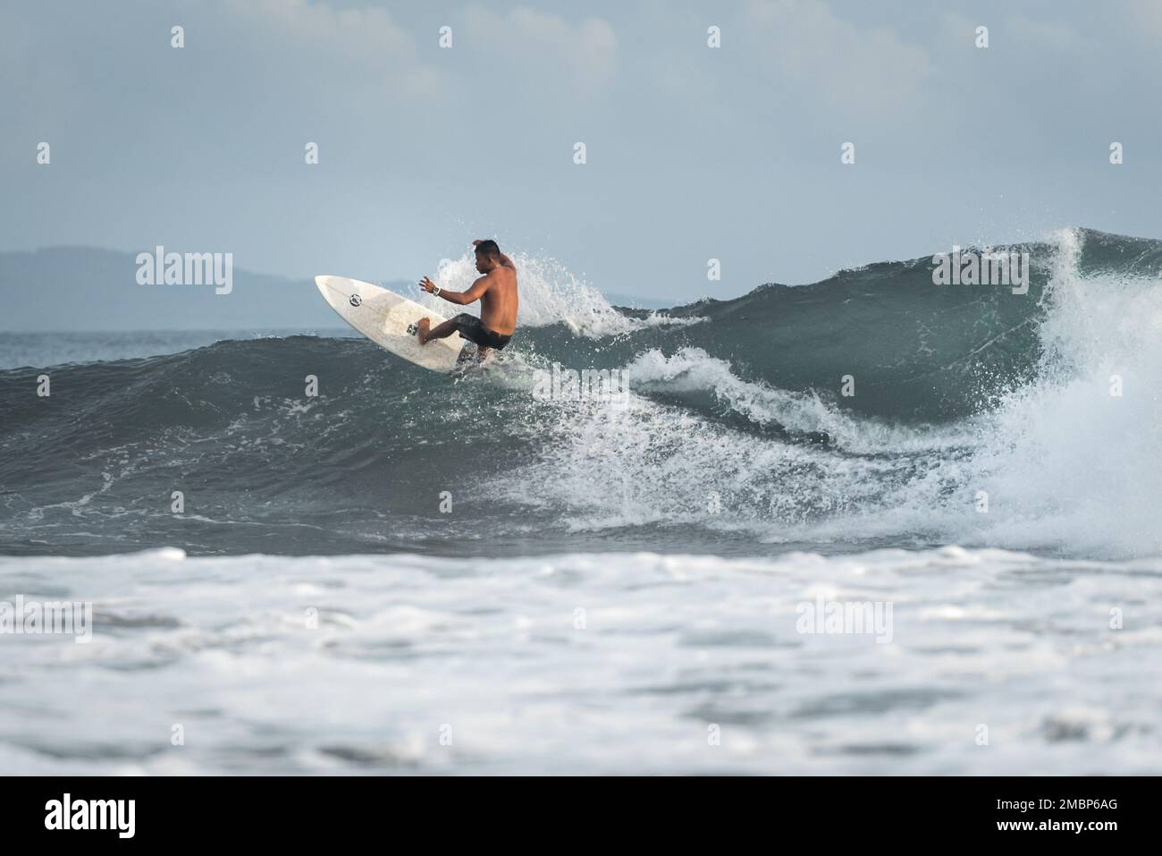 Surf a Keramas Beach, Bali, Indonesia, uomo e donna surf onde con un surf board, imparare surf a Kuta e Uluwatu Foto Stock