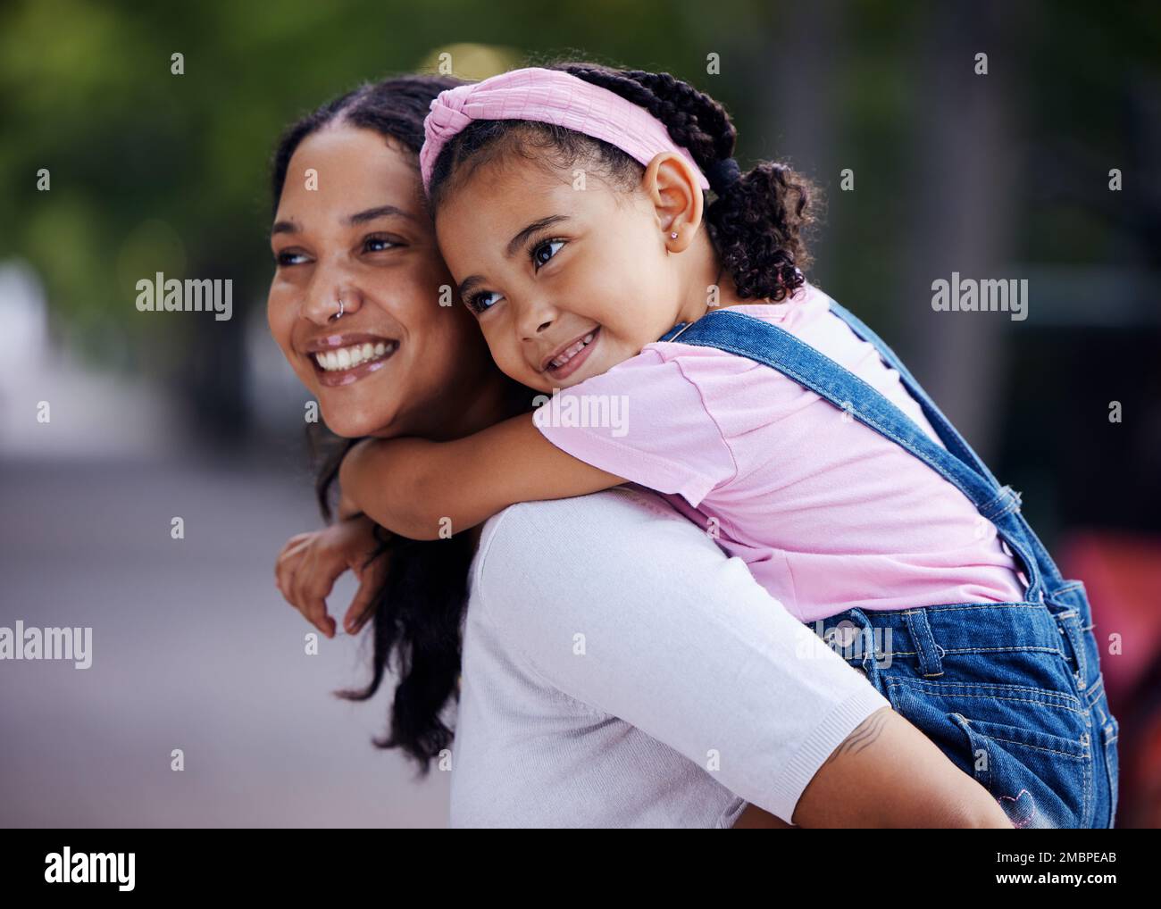 Mamma, bambina e felice con un giro in piggyback in un parco urbano, strada e all'aperto per amore, legame e cura. Famiglia, madre e figlia con sorriso Foto Stock
