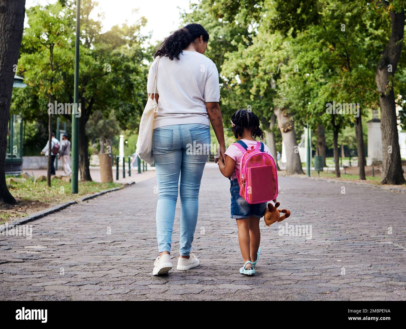 Madre, bambino e camminare con lo zaino che tiene le mani a scuola per la sicurezza nel parco all'aperto. Mamma con bambina o figlia che ha una passeggiata Foto Stock