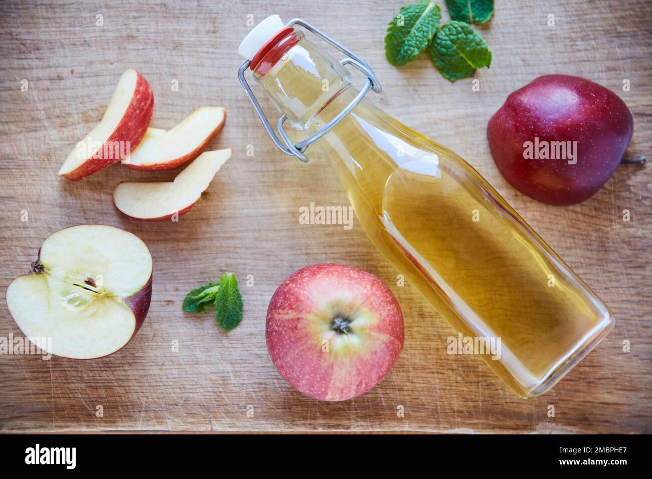 Detox della natura. Shot di una bottiglia di aceto di sidro di mela su un tavolo di legno. Foto Stock