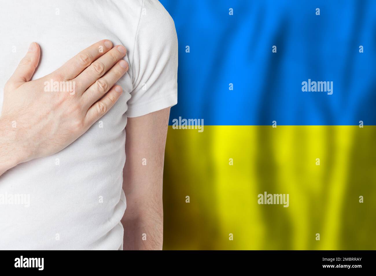 Persona Ucraina con mano sul cuore sullo sfondo della bandiera Ucraina. Patriottismo, paese, nazionale, orgoglio concetto Foto Stock
