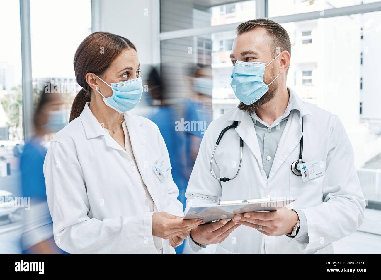 Procediamo con questo piano di trattamento. due medici che passano attraverso le note in un ospedale occupato. Foto Stock