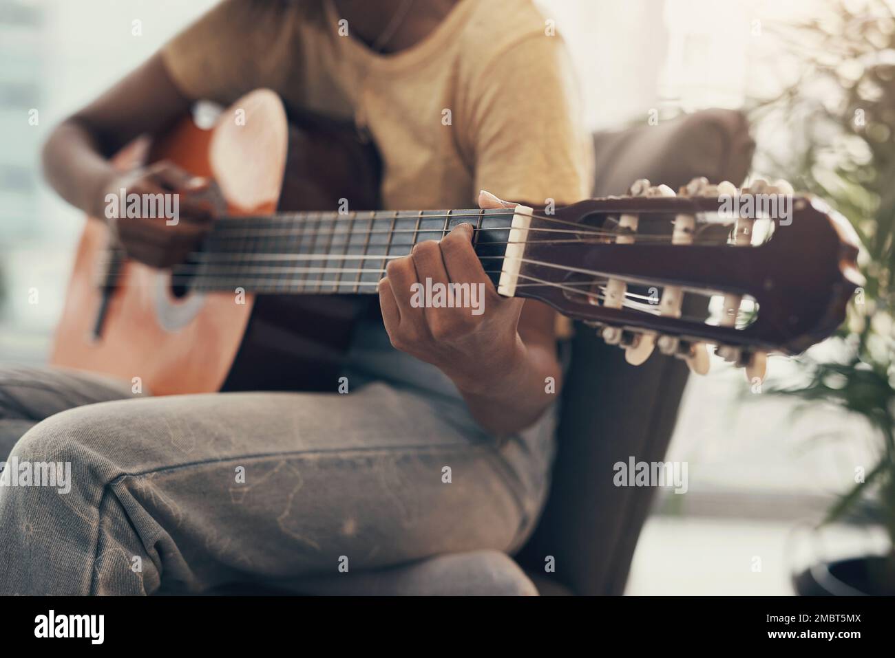 Il trucco per imparare è sentirlo. una donna irriconoscibile che suona la chitarra a casa. Foto Stock