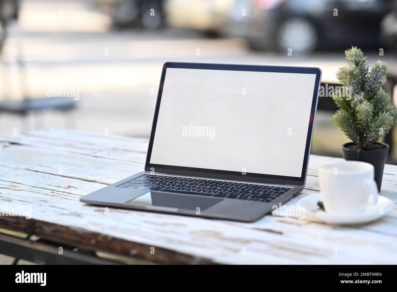 Computer portatile con schermo bianco vuoto e una tazza di caffè su un tavolo di legno rustico Foto Stock