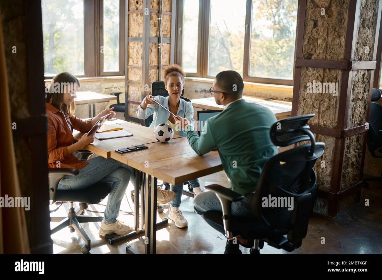 Un team multietnico giovane e diversificato che discute di un progetto nello spazio di coworking Foto Stock