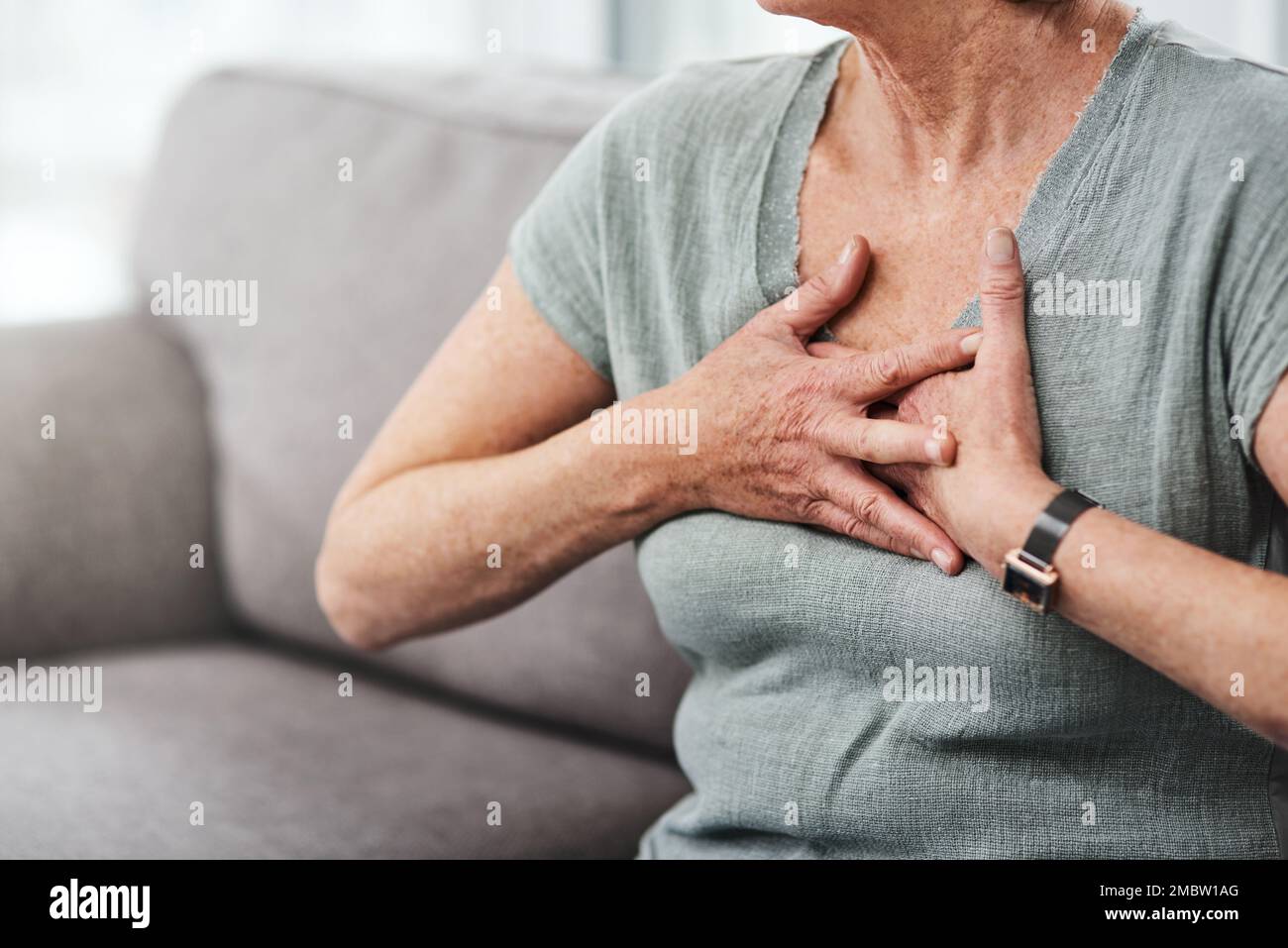 Proteggi il tuo cuore. una donna anziana che soffre di dolore toracico mentre si siede sul divano a casa. Foto Stock