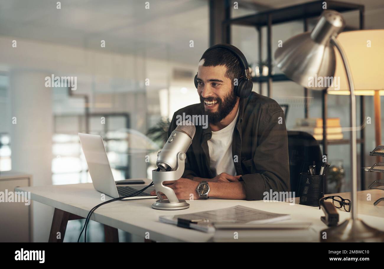 Lascia continuare il dialogo. un giovane uomo che usa un auricolare, un microfono e un computer portatile durante una notte tarda al lavoro. Foto Stock