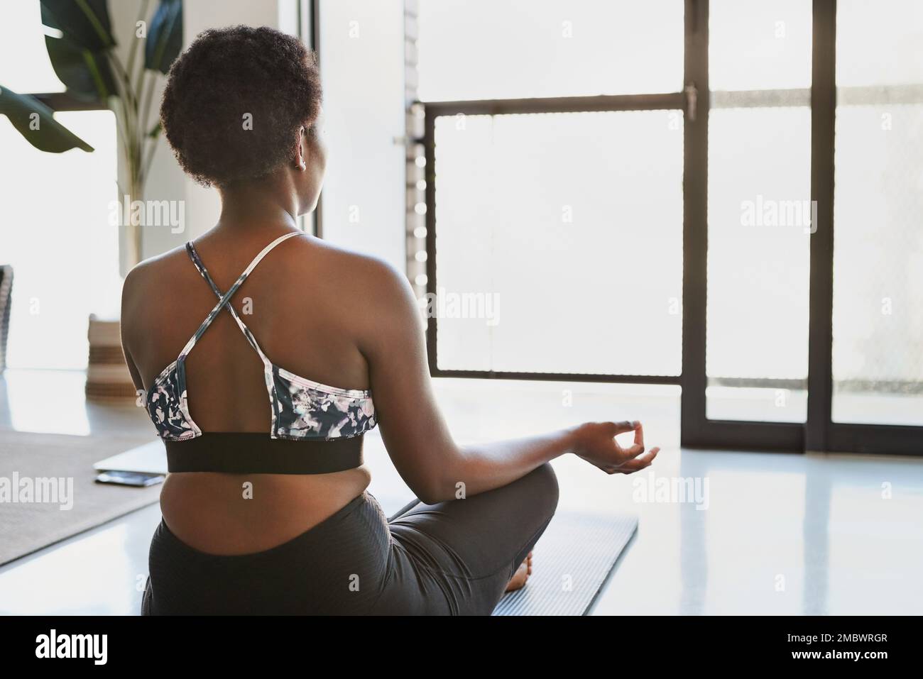 Rallenta e respira. Ripresa da dietro di una giovane donna meditante a casa. Foto Stock