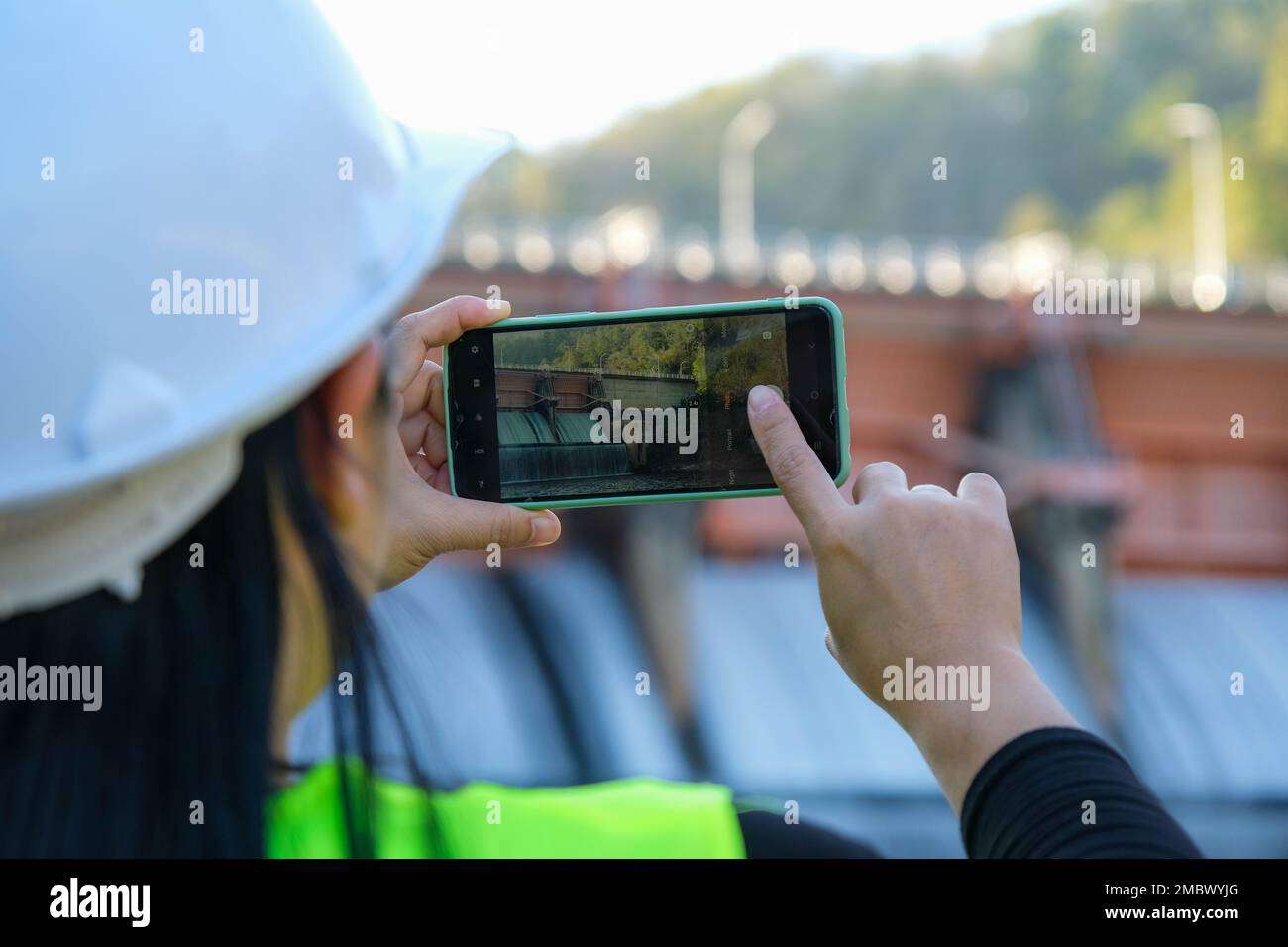 Gli ingegneri ambientali utilizzano i telefoni cellulari per scattare foto e registrare i dati che analizzano i contaminanti delle acque di diga. Concetto di acqua ed ecologia. Foto Stock