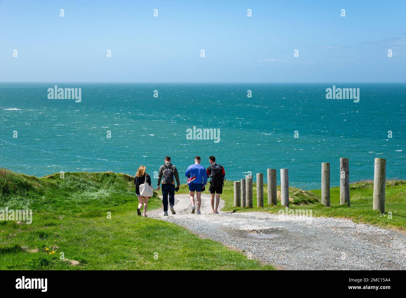 Quattro giovani che camminano lungo il sentiero costiero vicino a Morfa Nefyn sulla penisola di Lleyn, Galles del Nord. Foto Stock