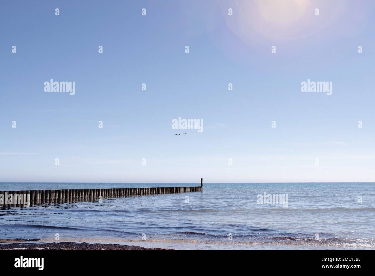 bellissimo sfondo mare, frangiflutti in legno in mare calmo su cielo blu chiaro Foto Stock