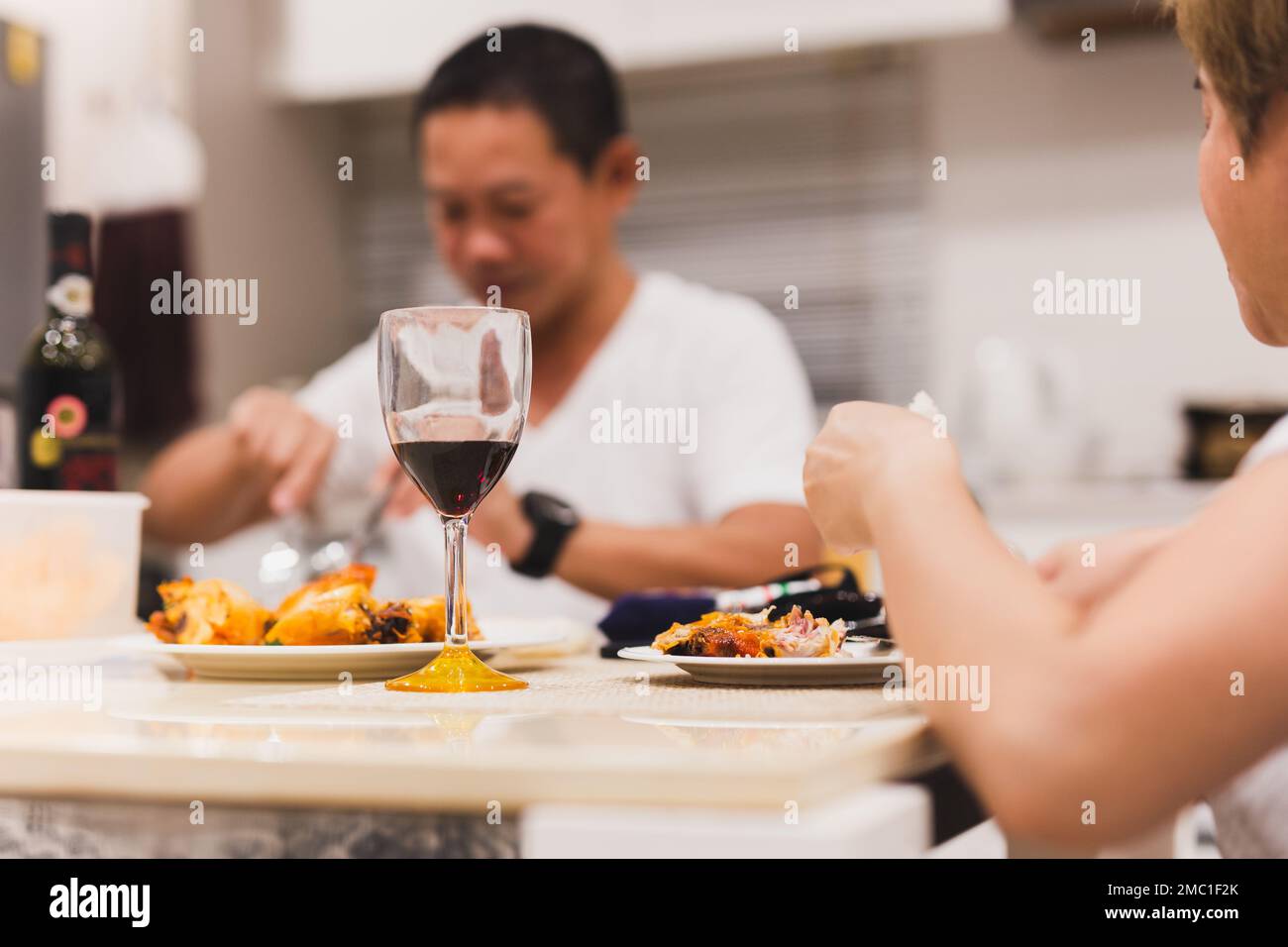 Coppia che ha una cena con bicchieri di vino rosso sul tavolo a casa. Foto Stock
