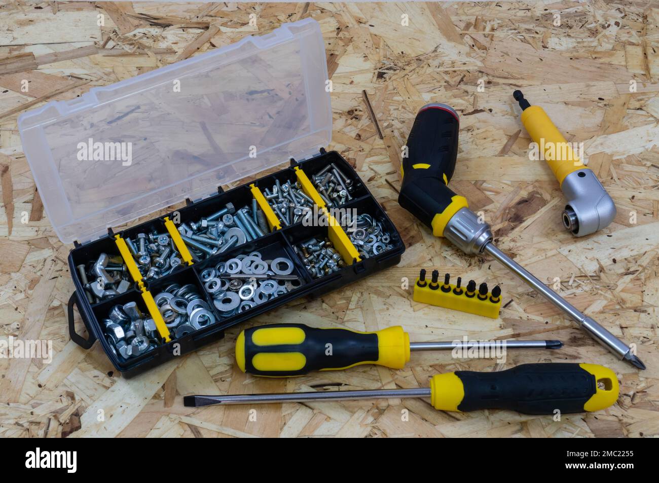 Organiser per valigie con dispositivi di fissaggio, cacciaviti e supporto con punte su fondo di una piastra di costruzione osb. Foto Stock