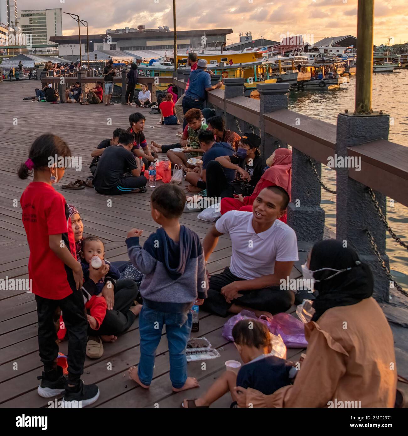 Famiglie socializzanti al tramonto lungo il lungomare di Kota Kinabalu, Borneo Foto Stock